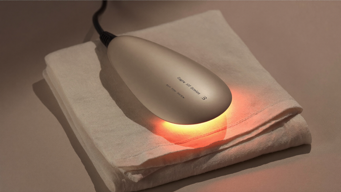 Appareil de luminothérapie LED posé sur un linge en lin ivoire, lumière chaude studio, esthétique clean beauty premium