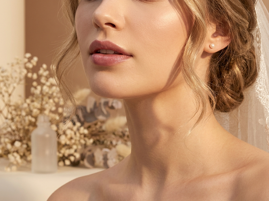 Gros plan sur des lèvres maquillées d'un tatouage peel-off rose mauve naturel, coiffure de mariée romantique en arrière-plan, lumière studio chaude sur fond ivoire et taupe