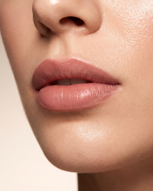 Gros plan élégant sur des lèvres teintées effet tatouage naturel, fond ivoire et taupe, lumière studio chaude